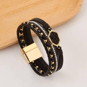Detail of multi-layer leather bracelet with gold beads, black stones and magnetic clasp