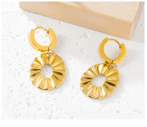 Detail of gold ruffle earrings with radial texture on a white textured background