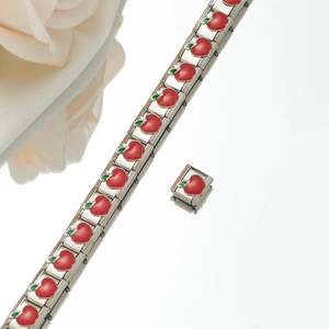 Detail view of Italian charm bracelet links featuring red enamel apple charms on steel