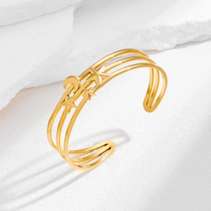 Dettaglio di un bracciale rigido dorato regolabile con motivi a luna e stelle