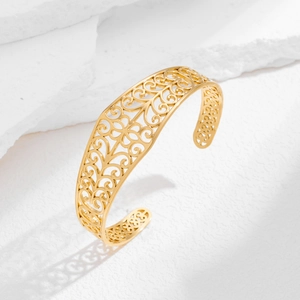 Detailopname van de gouden opengewerkte armband met verfijnde hart- en krulpatronen