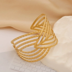 Detail of golden hollow wide cuff bangle with embossed beads on stone display