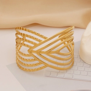 Detailed close-up of wide gold-plated stainless steel cuff bracelet with layered V-shape design