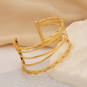 Detail of gold multilayer open cuff bracelet with twisted rope texture on stone display