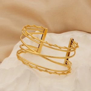 Macro detail of gold layered twisted wire open bangle with textured wave patterns