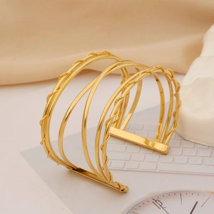 Detail of layered gold interwoven cuff bracelet with textured rope and mirror finish