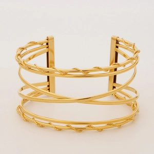 Detail view of multi-layer hollow wide gold bangle with twisted rope textures