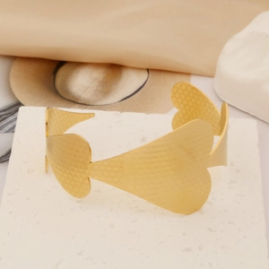 Detailed view of wide gold heart-shaped cuff bracelet with starburst engraving