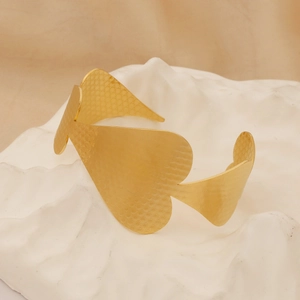 Close-up of gold heart-shaped hollow bracelet with detailed inner embossed texture