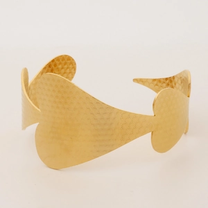 Detailed view of wide cuff gold bangle featuring hollow heart patterns and star texture