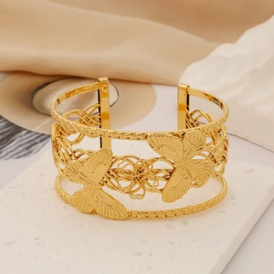 Detail showing hollow butterfly pattern on golden stainless steel wide cuff bracelet