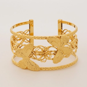 Detail of a hollow gold-plated butterfly bangle with intricate texture and polished finish