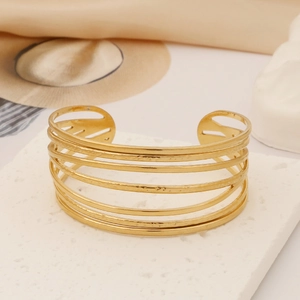 Macro detail of wide hollow gold cuff bracelet with hammered texture on stone display