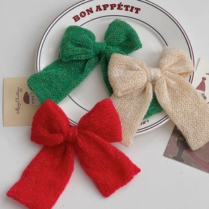 Detail of knitted Christmas bow ornaments in red, green and cream with golden metallic yarn
