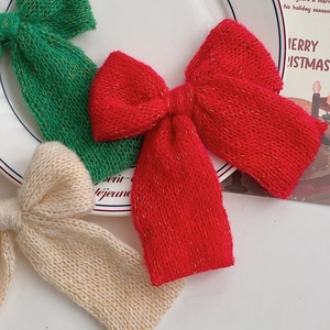 Detail of knitted Christmas bow ornaments with sparkling gold silk in red, green and cream