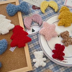 Flat lay of soft plush Christmas DIY accessories like stars and trees on a ceramic plate