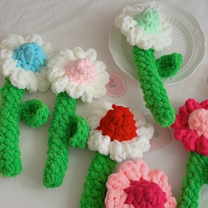 Close-up of handmade crochet chamomile flowers in various colors on a white texture fabric