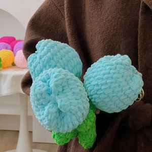 Detail einer hellblauen handgestrickten Häkel-Tulpe mit leuchtend grünen Blättern