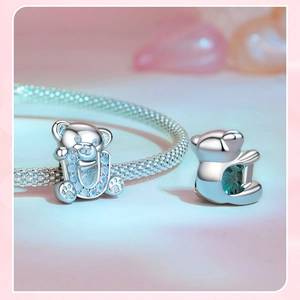 Macro detail of 925 silver teddy bear charm with gradient blue crystals on a mesh bracelet