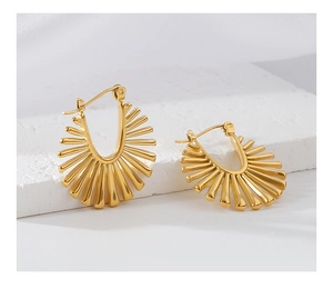 Macro detail of golden irregular sunburst earrings with radiant textured patterns