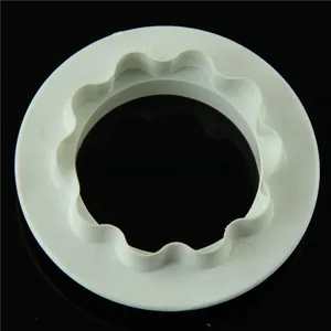 Detail view of a white plastic round cookie cutter with scalloped edges for DIY baking