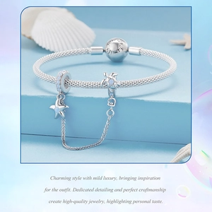 Detail of silver mesh bracelet with sea turtle and star pendants featuring blue opal accents