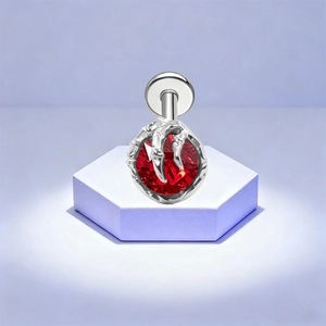 Detail of G23 titanium piercing jewelry featuring a red stone held by silver dragon claws