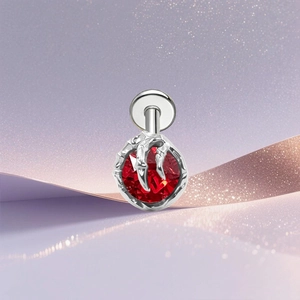 Macro detail of G23 titanium ear stud featuring a red zircon held by silver dragon claws