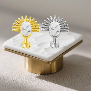 Dettaglio dei piercing labbro in acciaio inossidabile a forma di sole con pietra turchese