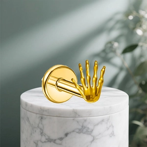 Polished gold G23 titanium palm skeleton ear stud on a white marble display stand