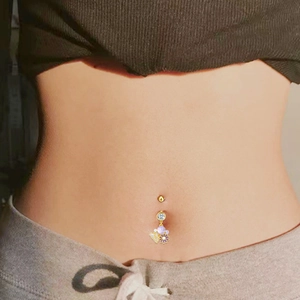 Piercing ombelico dorato con margherita viola e farfalla bianca indossato