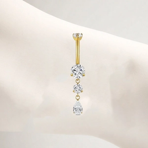 Detailed view of golden titanium belly ring featuring drop-shaped cubic zirconia dangles