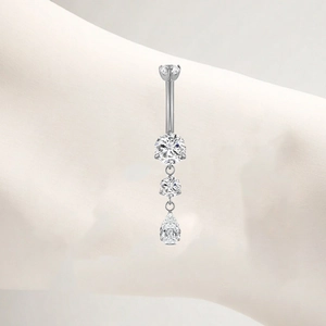 Macro shot of silver titanium belly ring featuring sparkling teardrop and round zircons