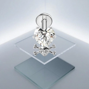Detail van G23 titanium navelpiercing met hartvormige zirkoon en schedel hanger