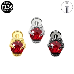 Detail view of G23 titanium ear studs with heart bat wings and red gems in three colors