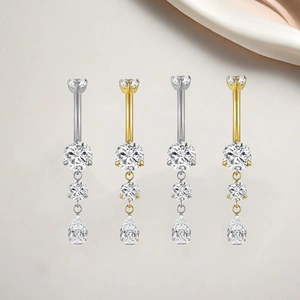 Detailed view of titanium belly rings with teardrop cubic zirconia in silver and gold set