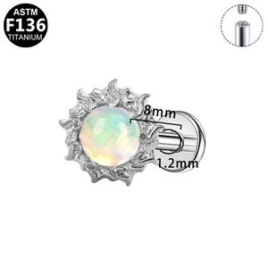 Macro detail of G23 titanium labret stud with fire sun design and opal stone inlay