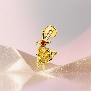 Detailed macro view of a gold-tone G23 titanium rose dagger labret with a tiny red gemstone
