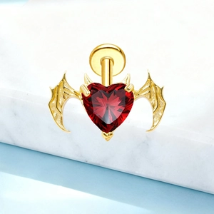 Macro shot of G23 titanium heart-shaped red zircon stud with golden bat wings
