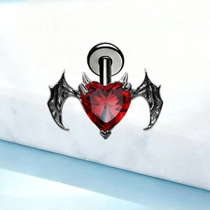 Macro shot of G23 titanium gothic bat wing stud featuring a red heart-shaped gemstone