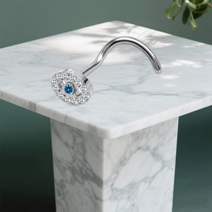 Detail eines S-förmigen Nasenpiercings mit blauem Zirkonia-Auge und weißen Kristallen