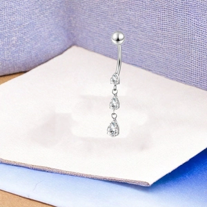 Macro detail of F136 titanium belly ring with three hanging pear-shaped zircon stones