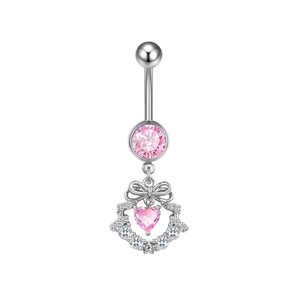 Macro detail of belly ring with pink heart gem and decorative silver bow accent