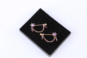 Macro detail of rose gold nipple rings with purple star crystals and hanging chains