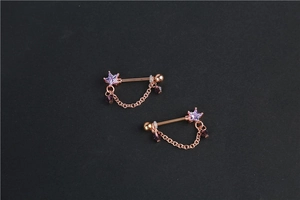 Detail of rose gold star nipple rings with purple crystals and teardrop pendants