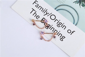 Detail of rose gold piercing with purple star zircon and hanging crystal chain charm