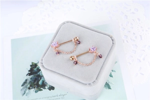 Detailed view of rose gold star-shaped nipple rings with purple crystals on velvet