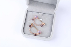 Detail of rose gold nipple rings with purple star zircon and elegant beaded chain links