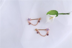 Detail of rose gold star nipple rings with purple zircon and elegant tassels on silk