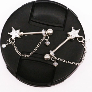 Detailed macro view of teardrop metal nipple rings with star-shaped zircon and hanging chains